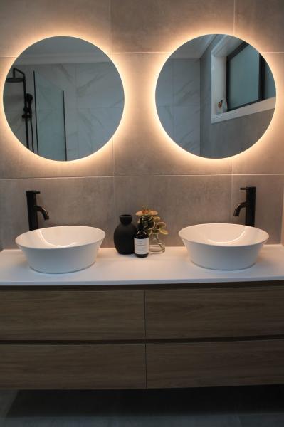 Double vanity with round backlit mirrors and vessel basins in a modern bathroom
