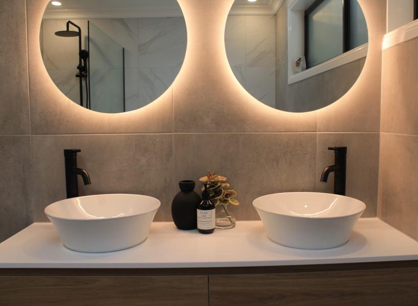 Modern double vanity bathroom with round backlit mirrors and matte black tapware