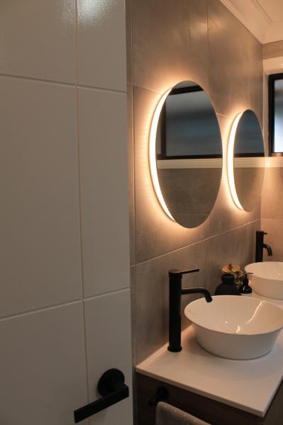 Modern bathroom vanity with two round backlit mirrors and vessel basins