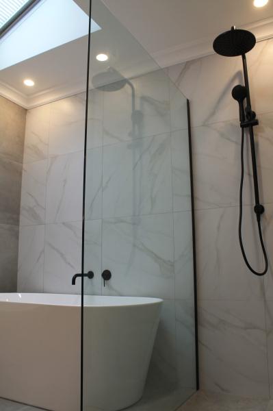 Modern bathroom with freestanding bath, frameless glass shower and black shower rail