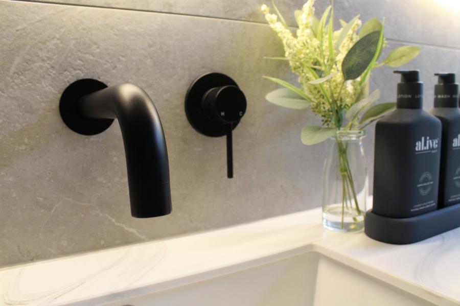 Matte black wall-mounted bathroom tapware beside a bath with modern styling