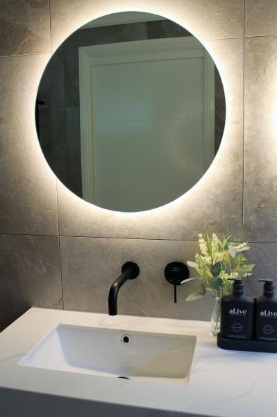 Modern bathroom vanity with illuminated round mirror and black wall-mounted tapware