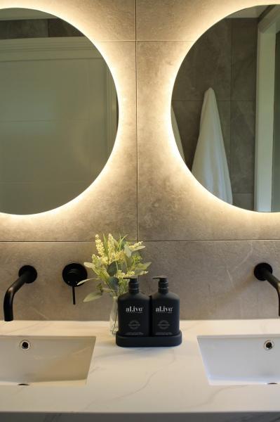 Double vanity bathroom with two backlit round mirrors and matte black tapware