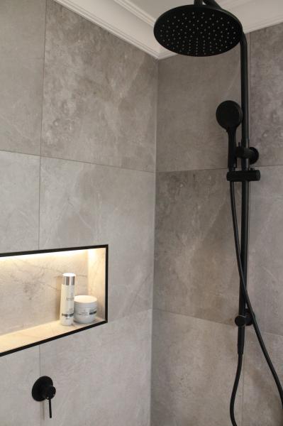 Modern walk-in shower with grey tiles, recessed niche and black shower set