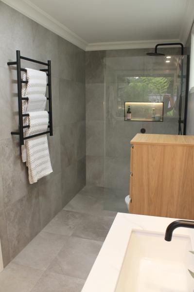 Modern grey tiled bathroom with walk-in shower, timber vanity and black tapware