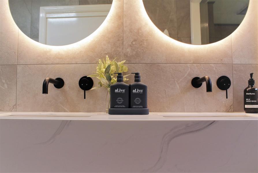 Double vanity wall with round backlit mirrors and matte black tapware