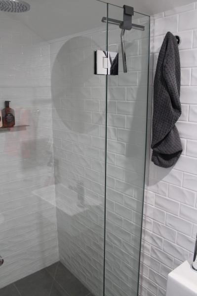 Frameless glass shower with chrome fittings and white subway tiles