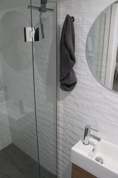Modern shower and vanity with white subway tiles and round mirror