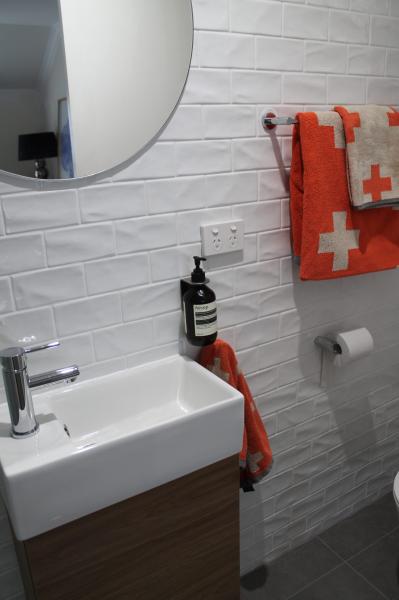 Modern bathroom vanity with round mirror, white wall tiles and coral towels