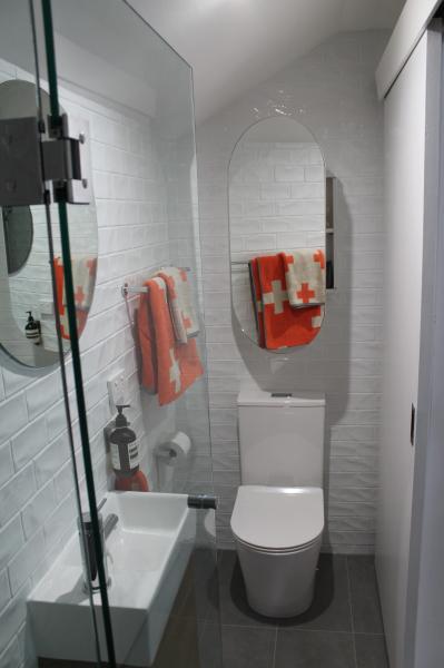 Modern white bathroom with bath, wall-hung toilet and arched mirror