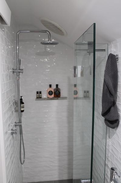 Walk-in shower with white wall tiles, niche shelf and frameless glass screen
