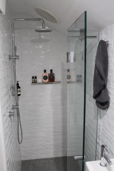 Modern walk-in shower with white textured tiles, glass screen and chrome fixtures