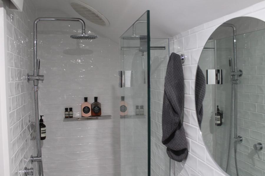 Modern white tiled shower with frameless glass screen and chrome fittings
