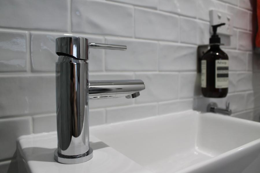 Chrome bathroom tap on a white basin with white subway tiles