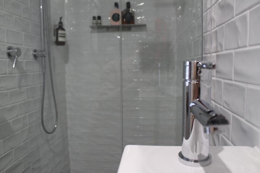 Modern white tiled shower with frameless glass screen and chrome tapware