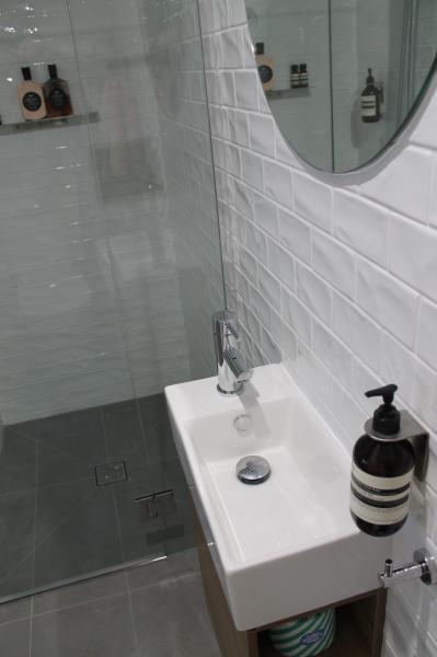 Modern white bathroom vanity beside a glass shower with subway wall tiles
