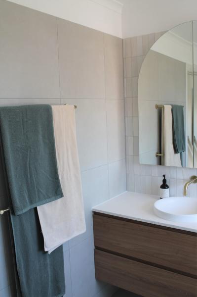 Modern bathroom vanity with arched mirror, white basin and grey towels