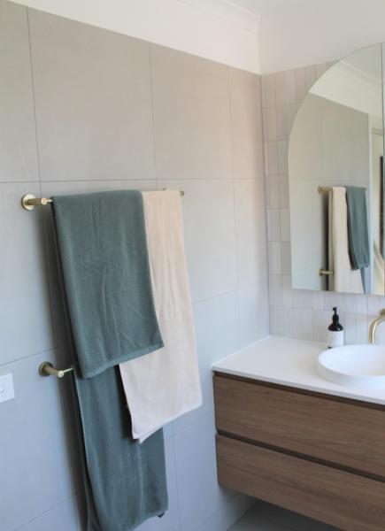 Modern bathroom vanity with arched mirror and heated towel rail