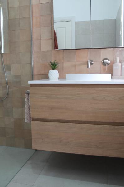 Modern bathroom vanity with timber drawers, white basin and blush wall tiles