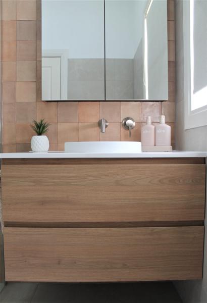 Modern bathroom vanity with timber cabinetry and terracotta tiles