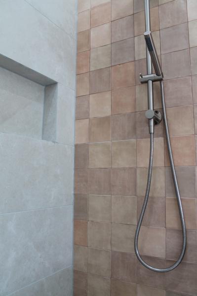 Tiled walk-in shower with handheld shower rail and recessed wall niche