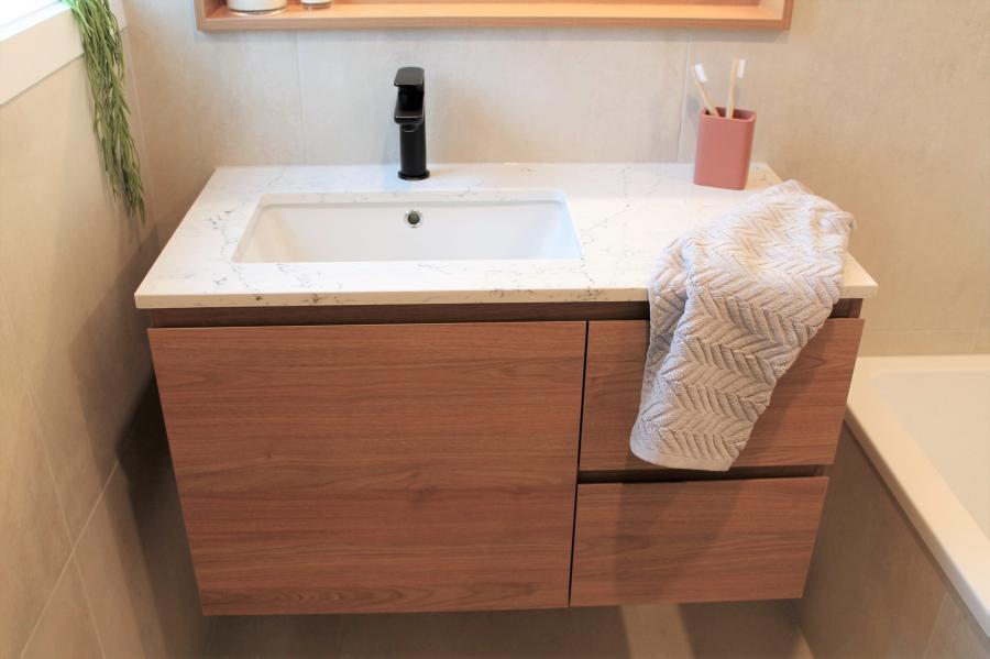 Floating timber vanity with white basin, matte black tap and towel in a modern bathroom