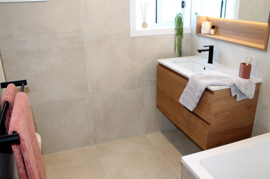 Modern bathroom with floating timber vanity, black tapware and soft beige wall tiles