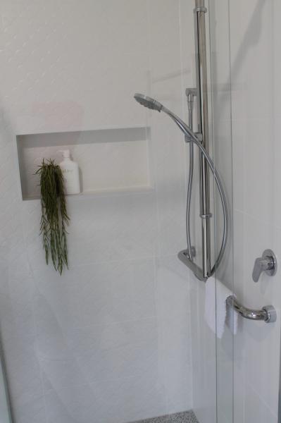 White tiled shower with recessed niche, chrome rail shower and grab handle