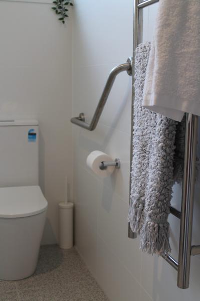Accessible bathroom with grab rail, toilet and towel rail beside a walk-in shower