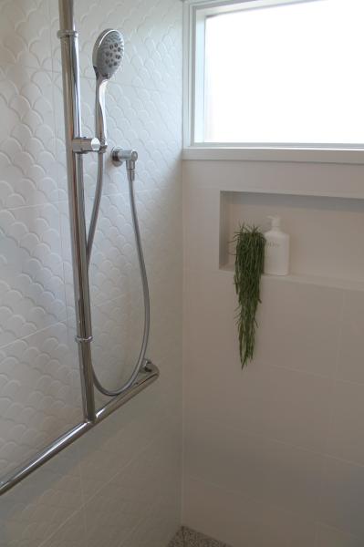 Walk-in shower with handheld shower rail, frosted window and recessed niche