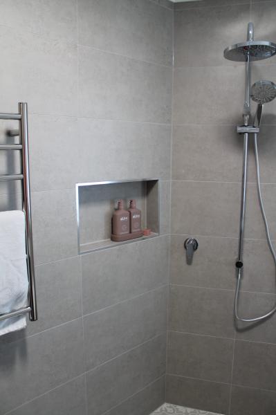 Grey tiled walk-in shower with recessed niche and handheld shower