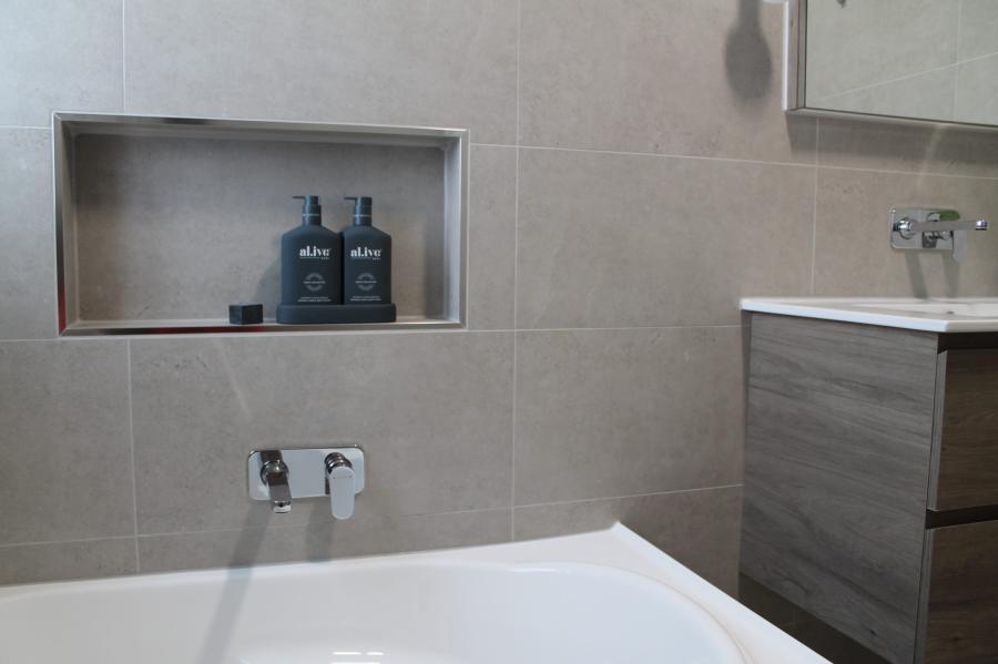Modern bathroom with built-in wall niche, bath and timber-look vanity
