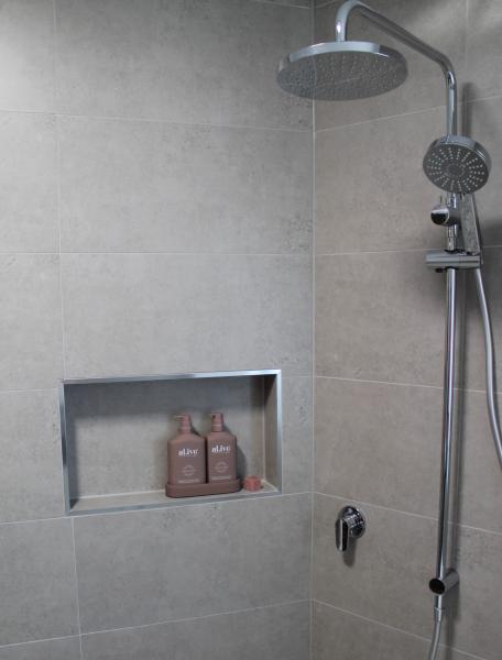 Grey tiled shower with recessed niche, rainfall head and handheld shower