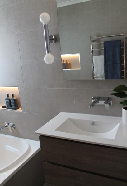 Modern bathroom vanity with integrated basin, mirror cabinet and brushed metal fittings