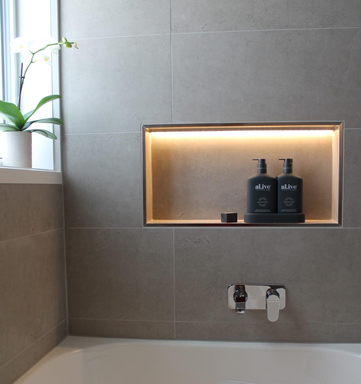 Modern bathroom shower niche with illuminated display and toiletries
