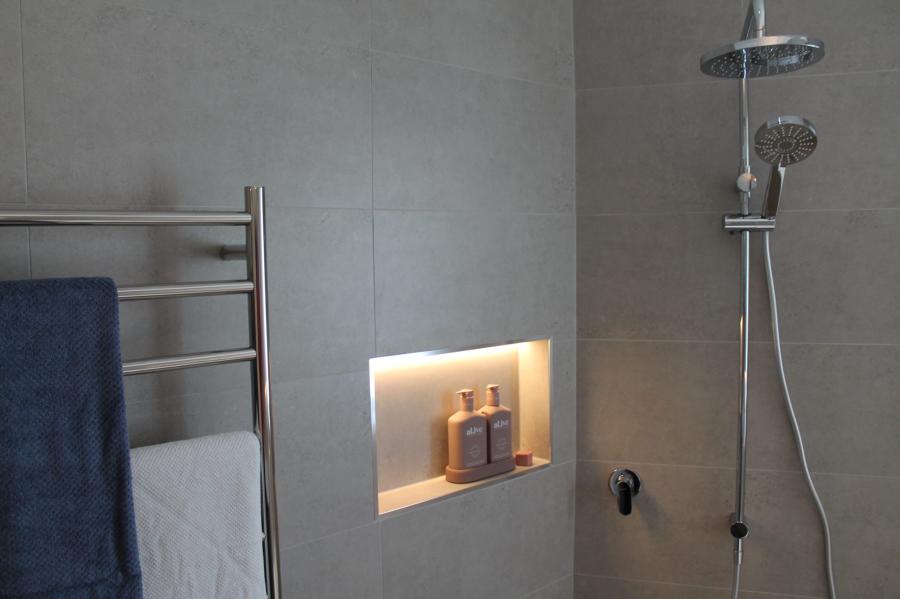 Modern grey tiled shower with recessed niche and chrome shower fittings
