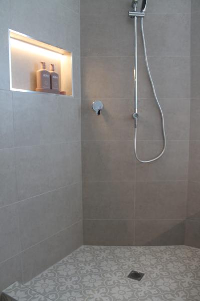 Walk-in tiled shower with recessed niche, handheld shower and patterned floor tiles