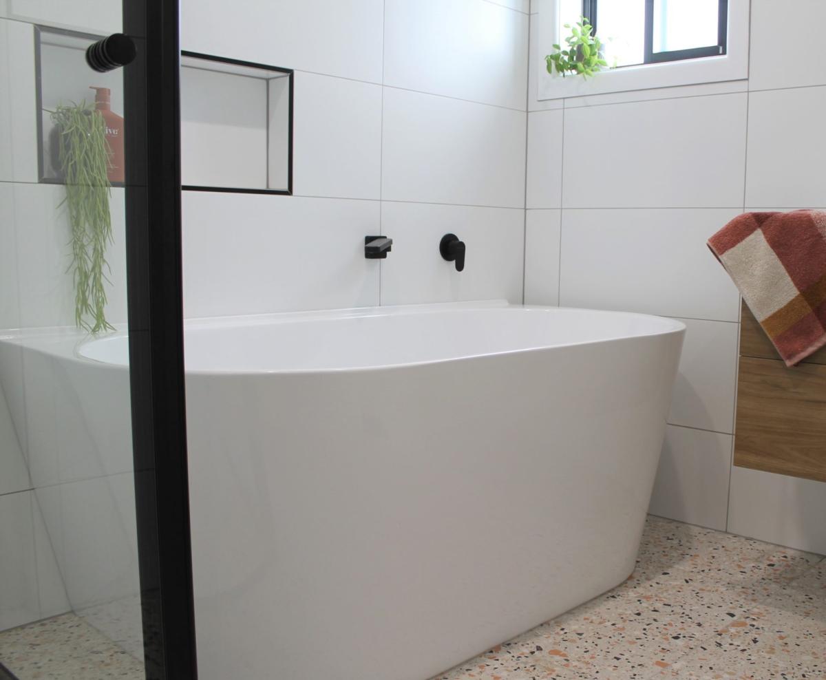 Modern freestanding white bathtub with black tapware