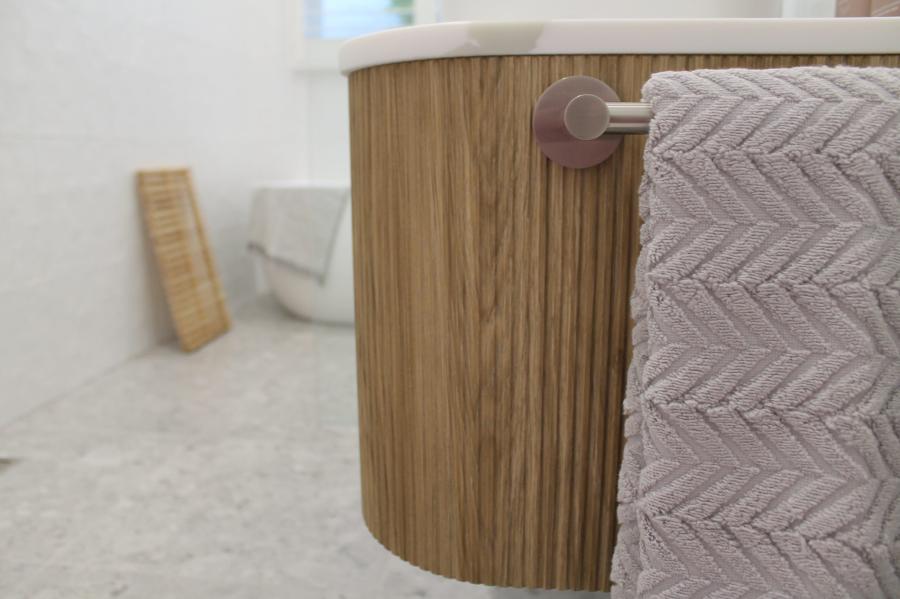 Curved timber bathroom vanity with textured towel in a bright modern bathroom