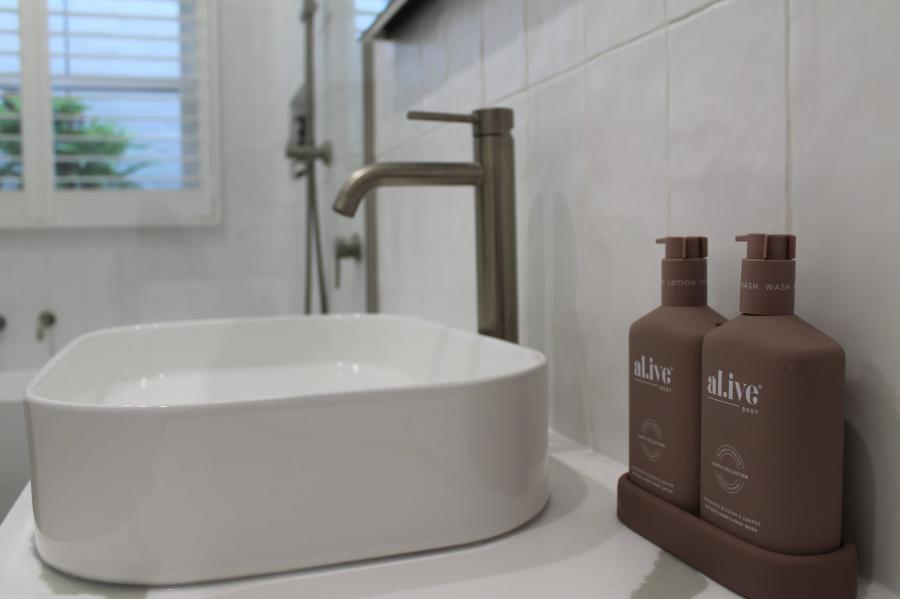 Modern bathroom vanity with vessel basin, brushed tapware and toiletry bottles