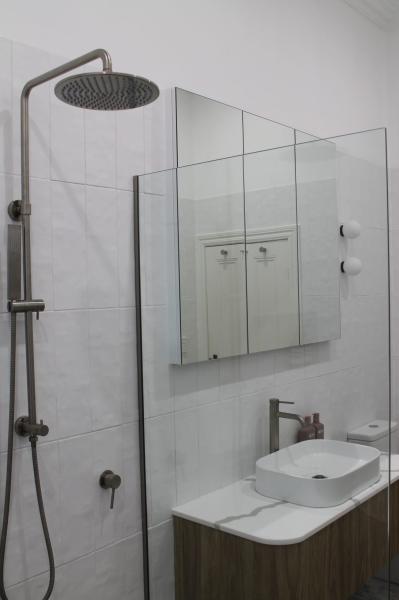 Modern white tiled shower and vanity with frameless glass screen and mirrored cabinet