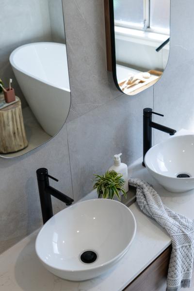 Modern bathroom vanity with vessel basins, black tapware and freestanding bath