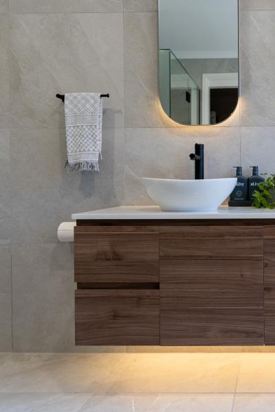 Modern bathroom vanity with vessel basin, round mirror, timber cabinet and soft under-cabinet lighting