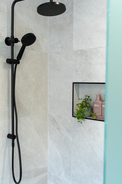 Matte black shower set with recessed niche in a light tiled bathroom