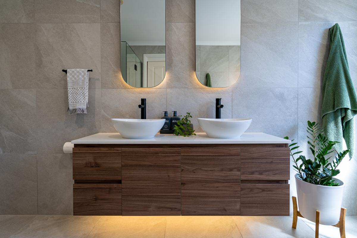 Modern bathroom vanity with double vessel basins, timber cabinetry and backlit mirrors
