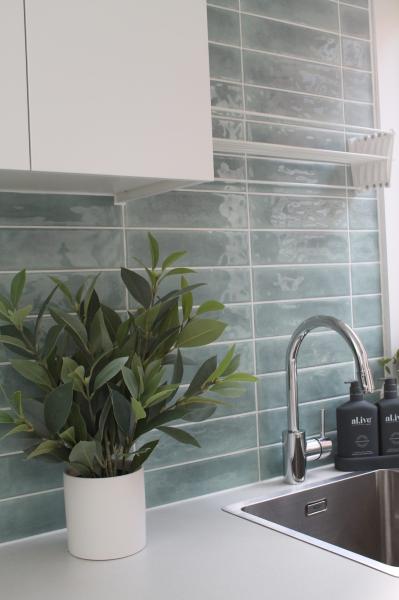 Green subway tile splashback with white cabinetry and chrome mixer tap