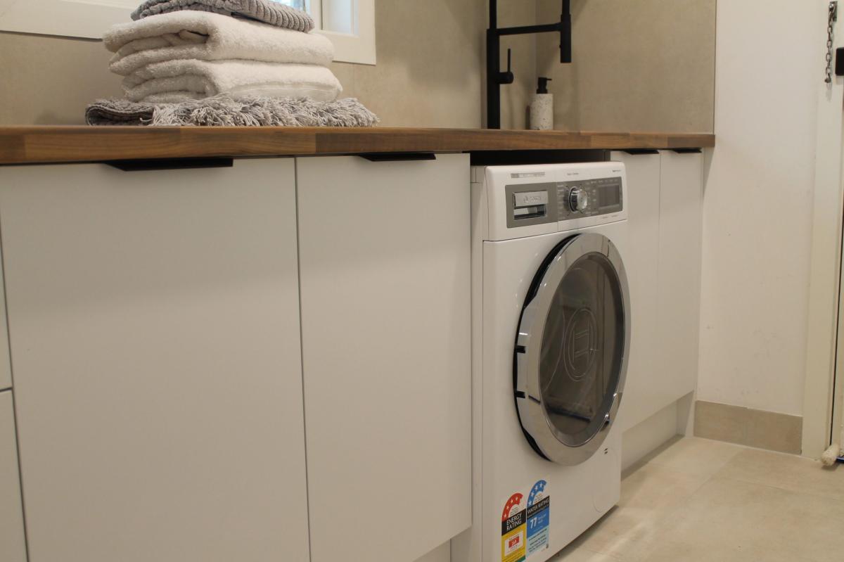 Modern laundry room with washing machine and timber shelf