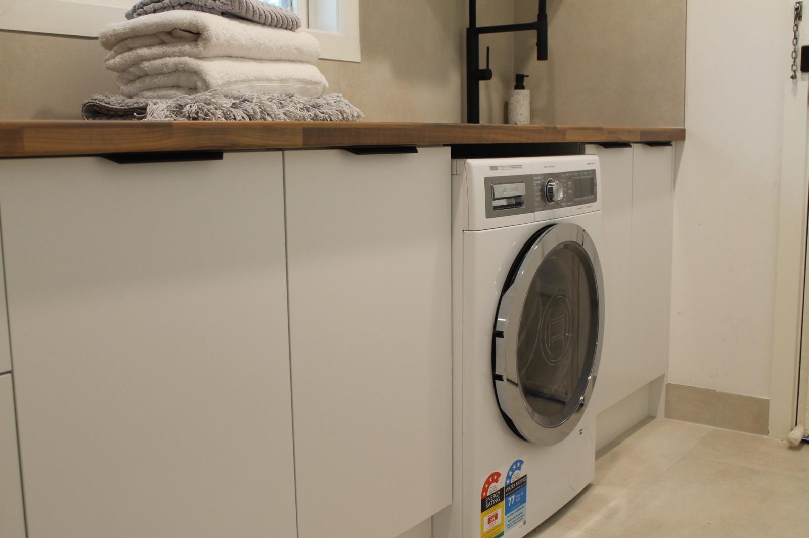 Modern laundry room with washing machine and timber shelf