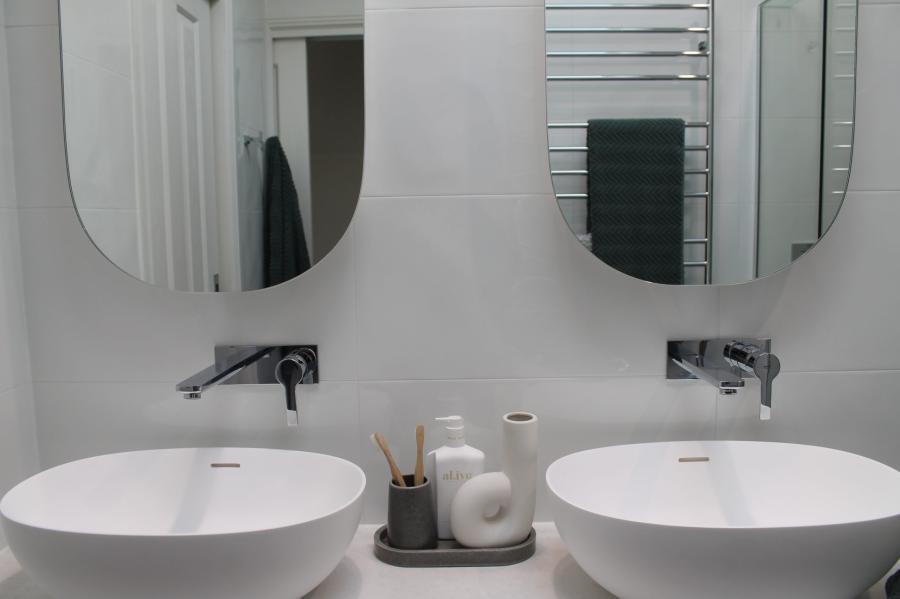 Double vessel basins with wall-mounted taps and round mirrors in a modern white bathroom