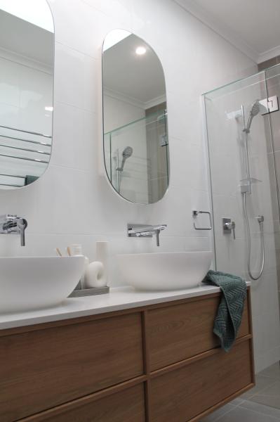 Modern bathroom vanity with vessel basin, arched mirror and glass shower